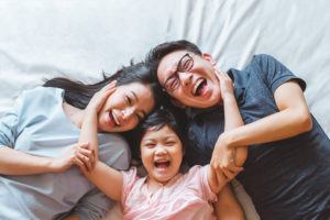 Happy Asian family laying on bed smile, top view